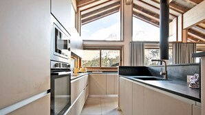 A modern kitchen with a central island, large windows, and a view of mountains.
