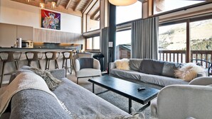 A modern living room with a sofa, a coffee table, and a dining area with bar stools.