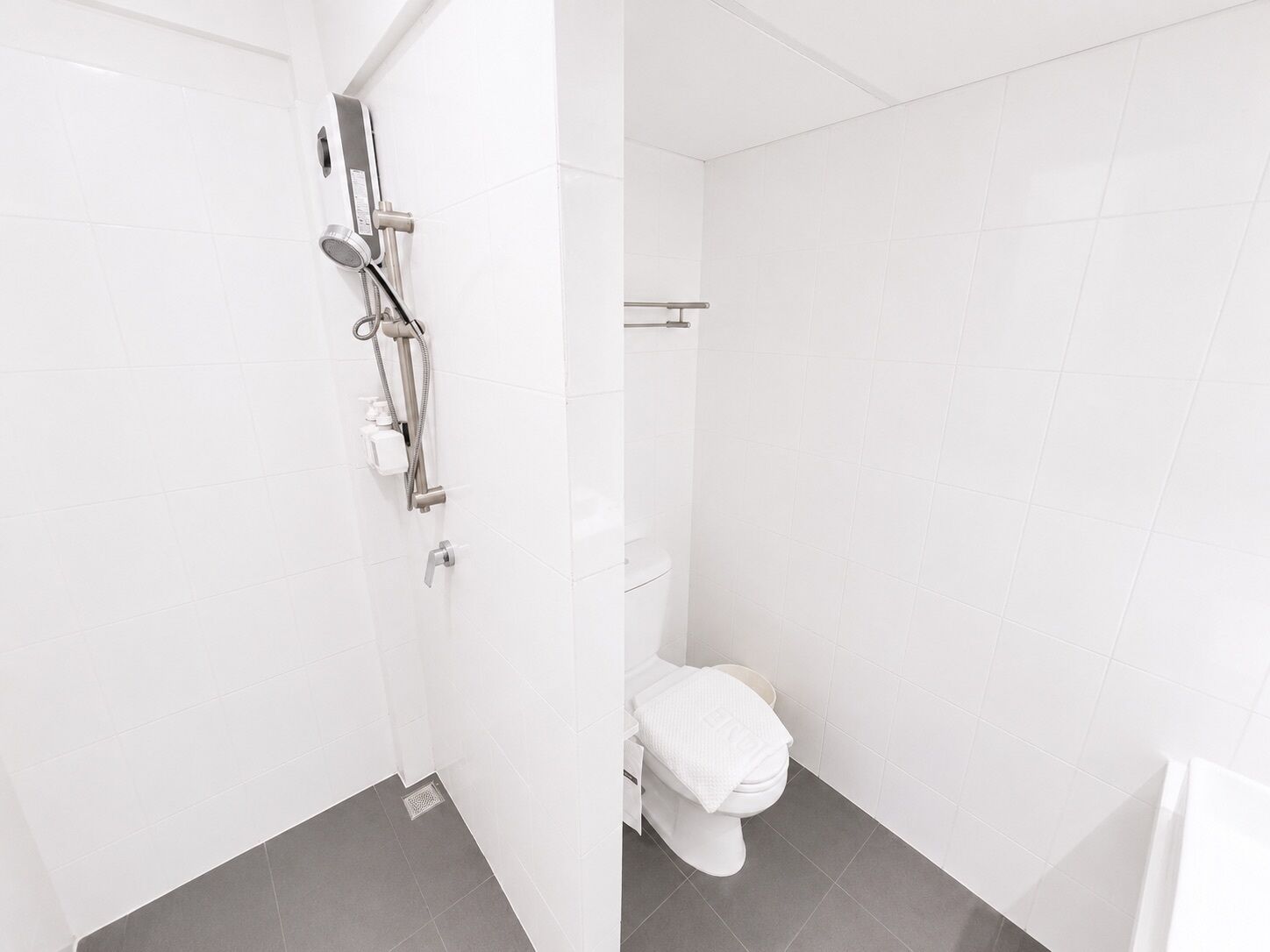 A bathroom with a shower, toilet, and a towel rack.