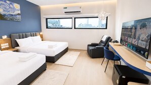 Habitación de hotel con dos camas, un escritorio con computadora, televisor y sillón de masaje.