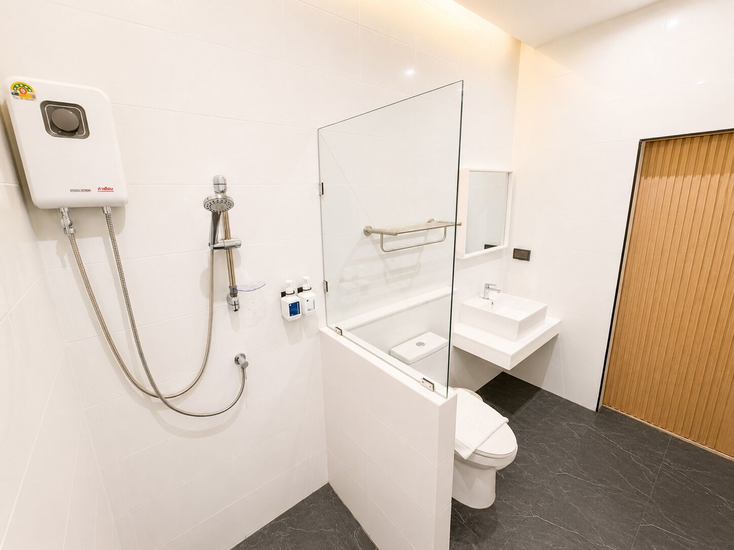A modern bathroom with a glass shower enclosure, a white sink, and a toilet.