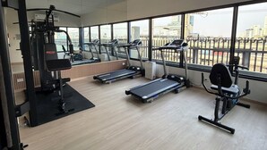 Un gimnasio con cintas de correr, máquinas de pesas y una máquina de remo.