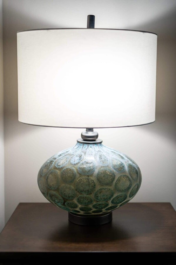 A table lamp with a textured base and a white lampshade on a wooden table. - Modern State Unit 2 (Traverse City)