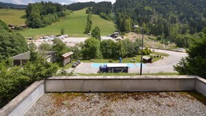 A rural landscape with a parking area, buildings, and a movecorp truck. - Cozy studio near slopes with private garage (Les Gets)