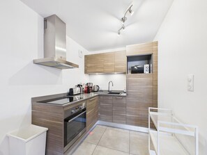 Una cucina moderna con forno integrato, forno a microonde e cappa aspirante in acciaio inossidabile.