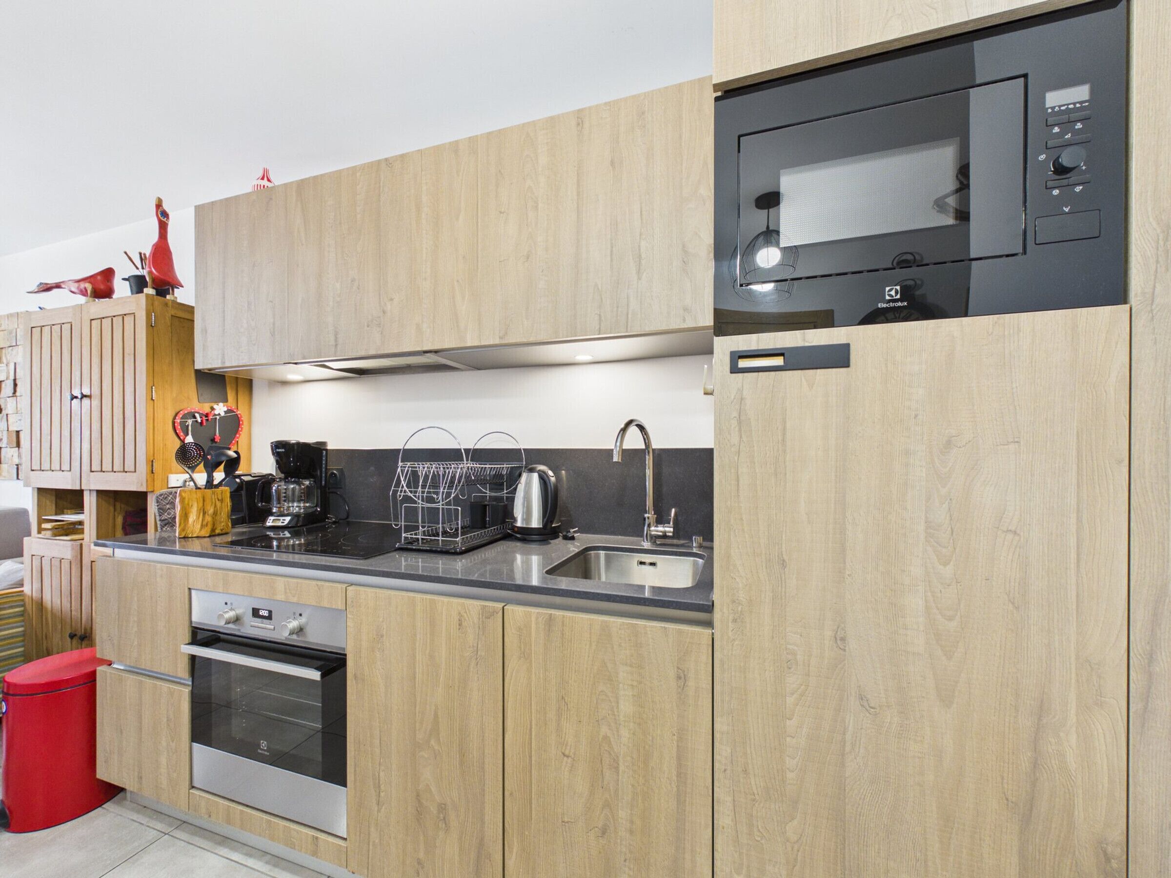 A modern kitchen with wooden cabinets, stainless steel appliances, and a built-in microwave.