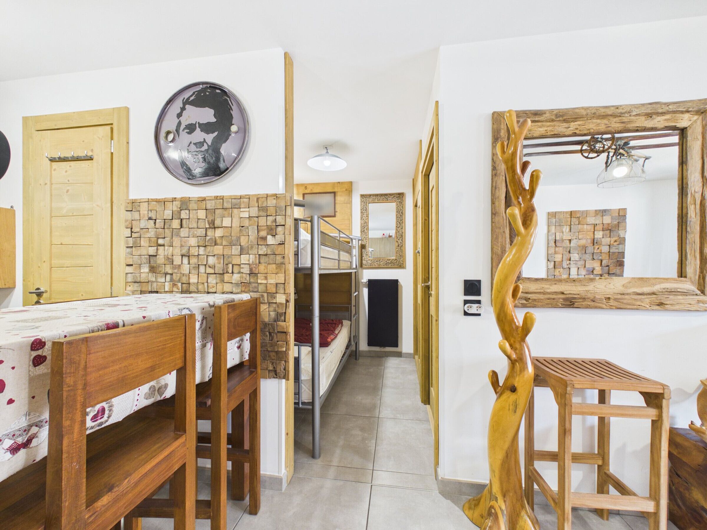 A room with bunk beds, a wooden table, a mirror, and a wall-mounted picture.