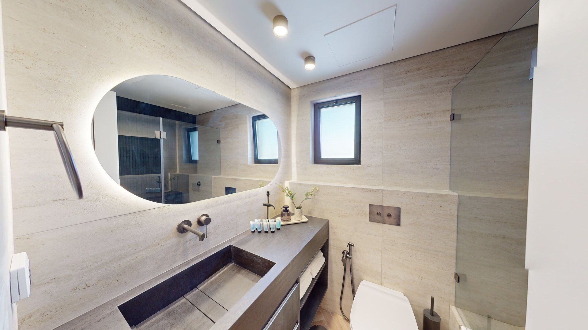 Une salle de bain moderne avec un grand miroir, un meuble-lavabo à deux vasques et un espace douche.
