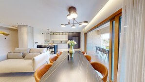 Una sala de estar moderna con comedor, cocina y un amplio ventanal con cortinas.