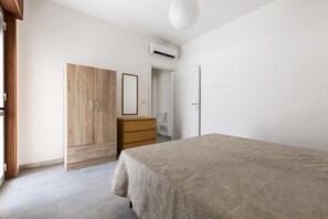 Ein Schlafzimmer mit Bett, Kleiderschrank, Kommode und Klimaanlage.