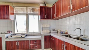 Een keuken met houten kastjes, een raam, een gootsteen en een fornuis.