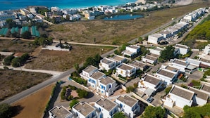 Ein Luftbild eines Küstenwohngebiets mit modernen Häusern, einer Straße und einem Strand im Hintergrund.