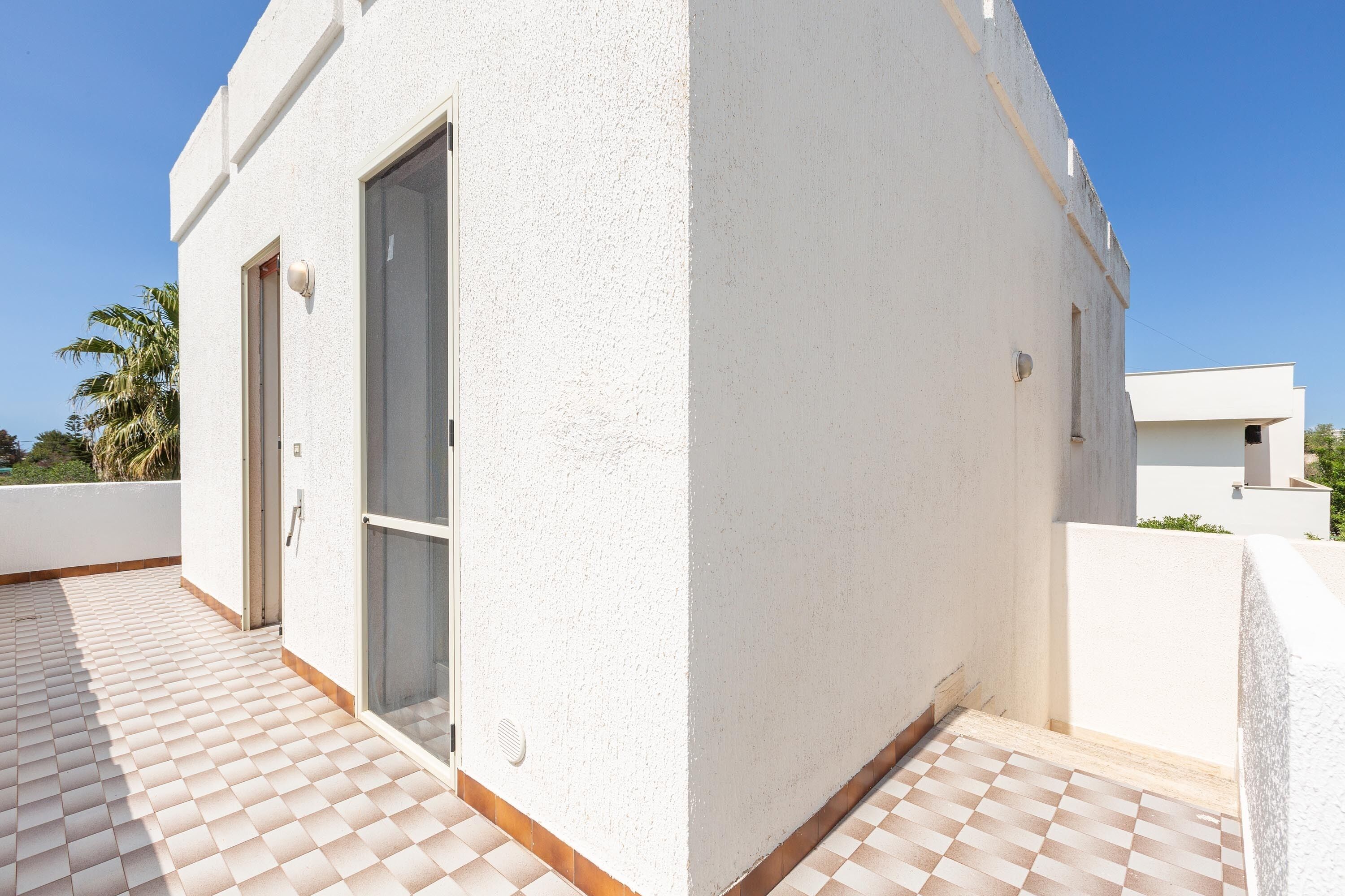 A white building with a tiled balcony and a door.