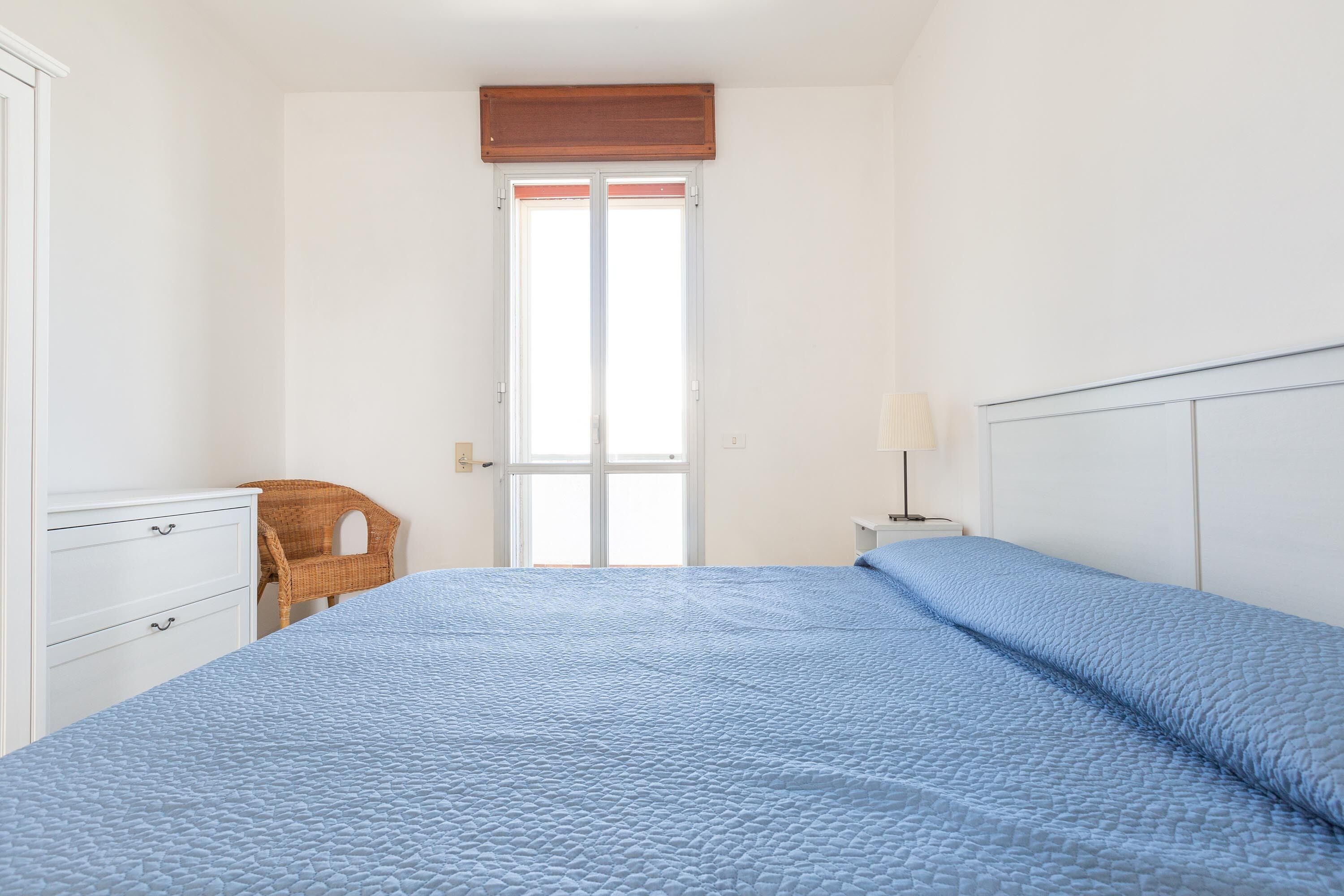 A bedroom with a bed, a dresser, a chair, and a window.