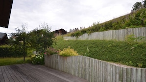 A wooden deck with a wooden fence and a garden with various plants and flowers.