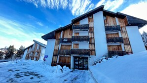 A multi-story building with wooden balconies, a snow-covered ground, and a clear sky.