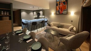 Una sala moderna con un sofá, una mesa de comedor para cuatro personas y una cocina al fondo.