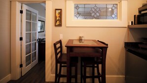 A dining area with a table and chairs, a window with a stained glass design, and a door leading to another room. - Relax in the luxurious 1-bedroom Louisa Suite at RedTail Inn. Enjoy a double rain shower, plush linens, and a shared hot tub. Located near downtown Ashland, with off-street parking and high-speed WiFi. (Ashland)