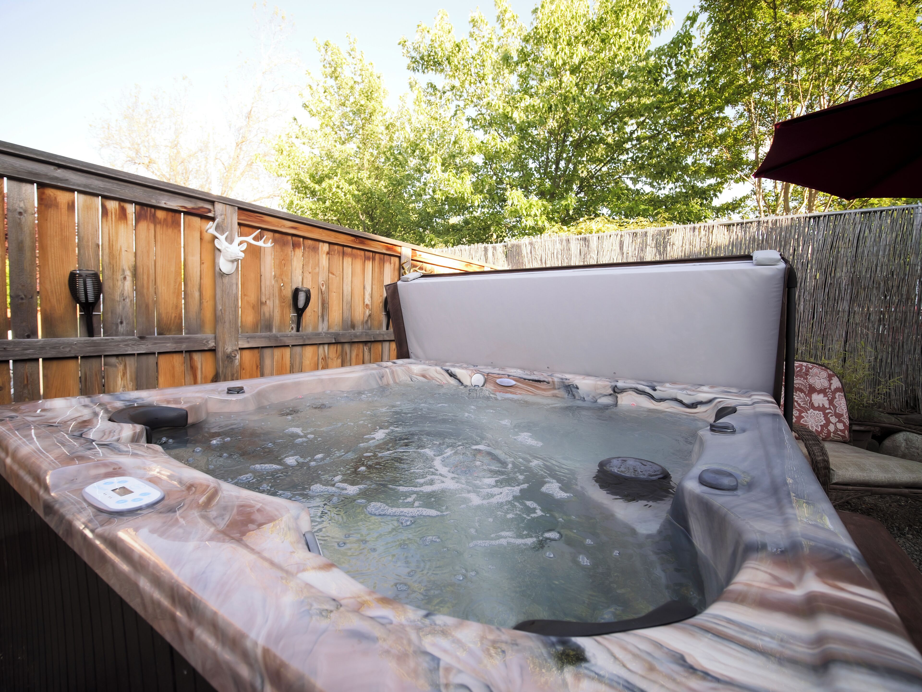 A hot tub with a wooden deck and a wooden fence in the background.