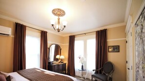 Ett hotellrum med en stor säng, en byrå med en spegel, en stol och ett skrivbord med en lampa.