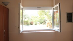 Een kamer met een groot raam, een houten garderobe en een wandlamp.