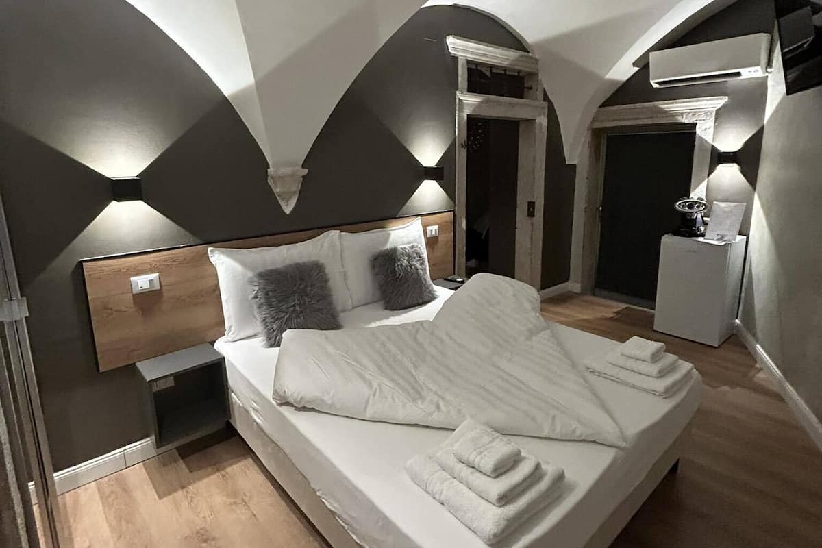 A modern bedroom with a large bed, a nightstand, a dresser, and a built-in wardrobe.