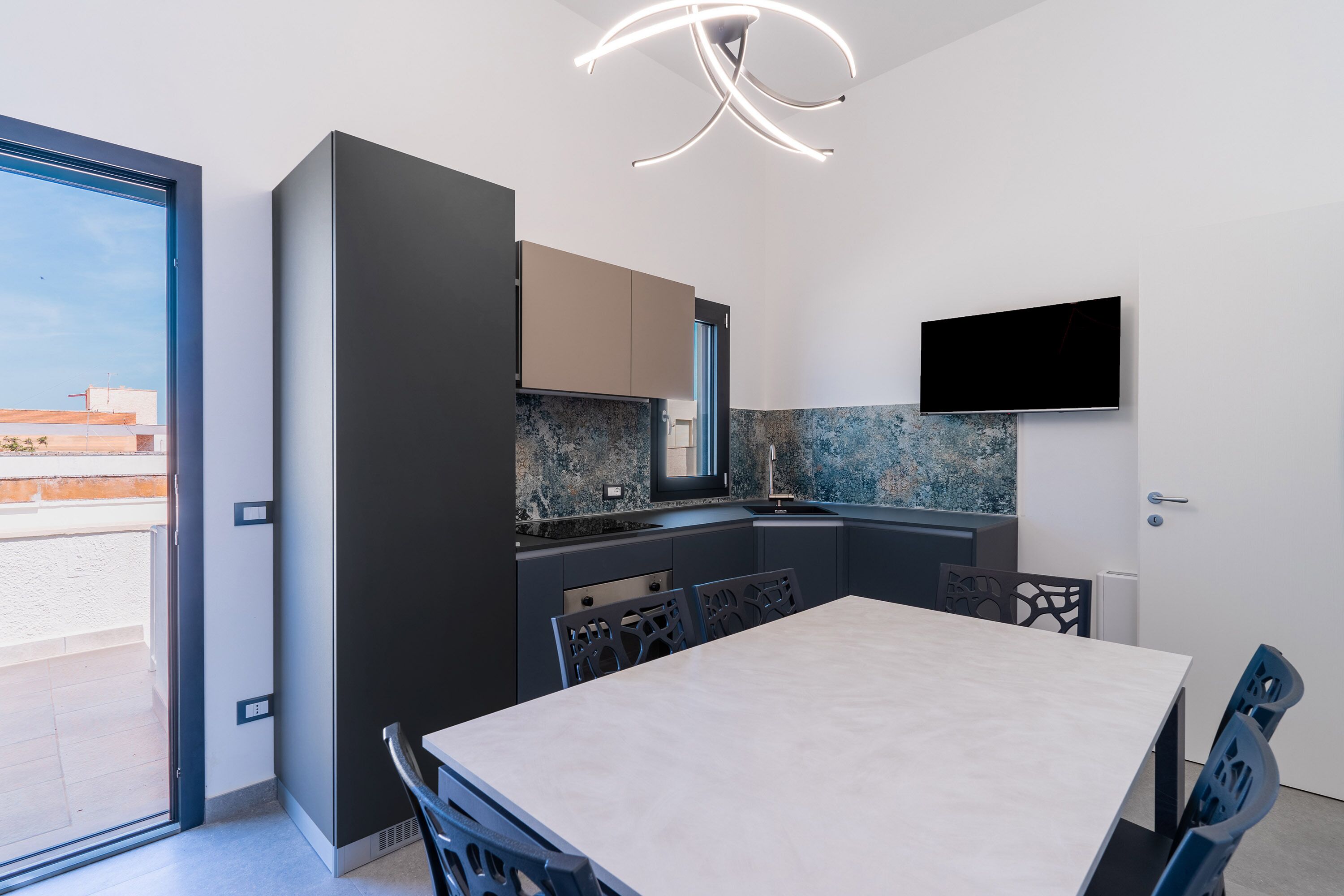 Een moderne keuken met een eethoek, een aan de muur bevestigde televisie en uitzicht op het omliggende landschap.