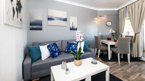 A modern living room with a grey sofa, blue and white patterned cushions, a white coffee table, and a dining area with a white table and chairs. - Beautiful Beachfront Apartment In Puerto Marina (Benalmádena)