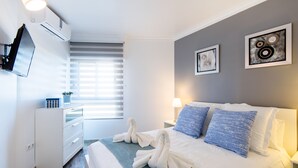 A modern hotel room with a bed, a dresser, a flat-screen TV, and artwork on the walls. - Beautiful Beachfront Apartment In Puerto Marina (Benalmádena)