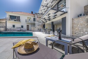 Relax by the pool surrounded by a patio with lounge chairs and a dining table for two.