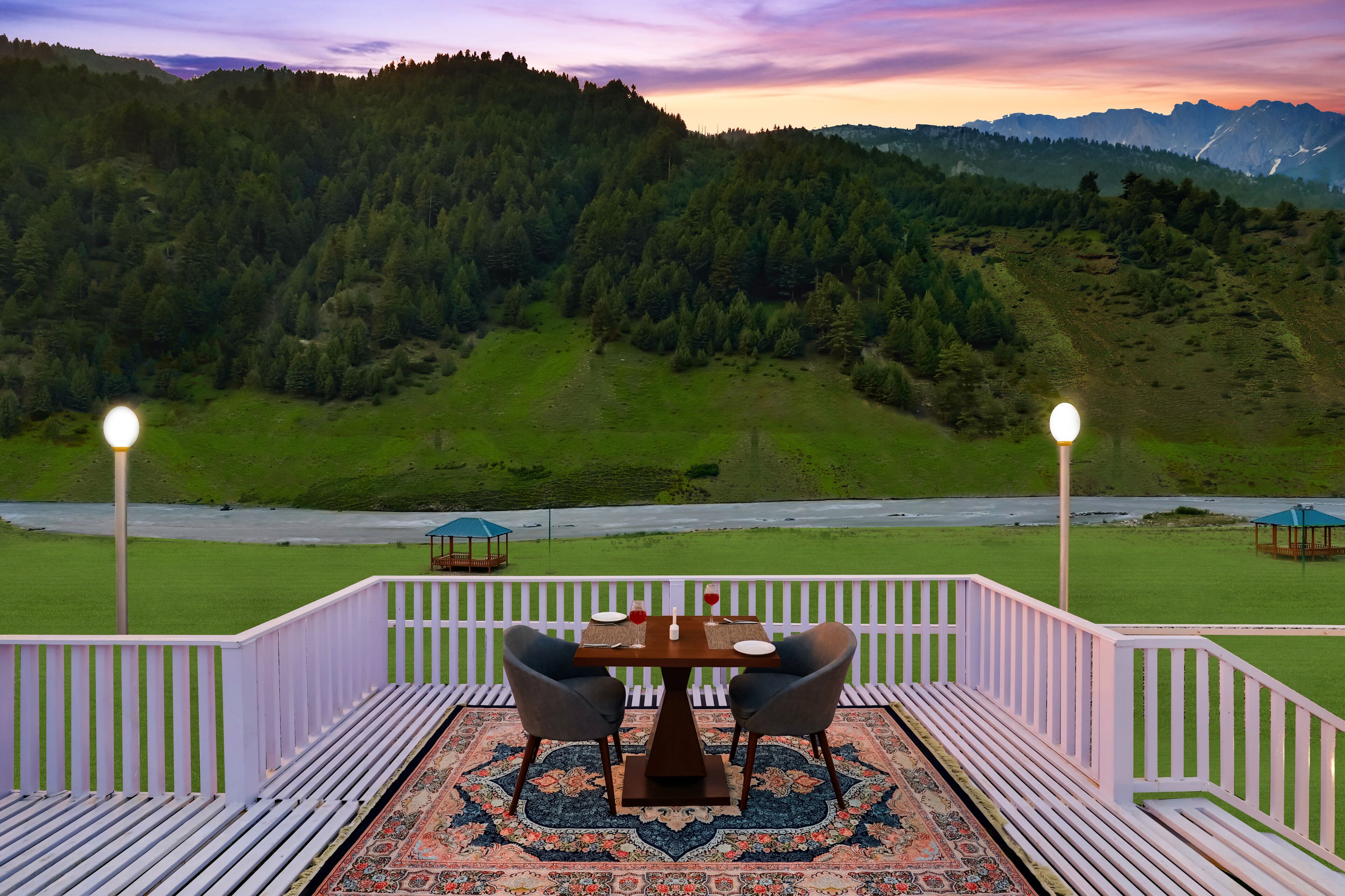 A terrace with a table and chairs, a patterned rug, and a view of a forested valley.