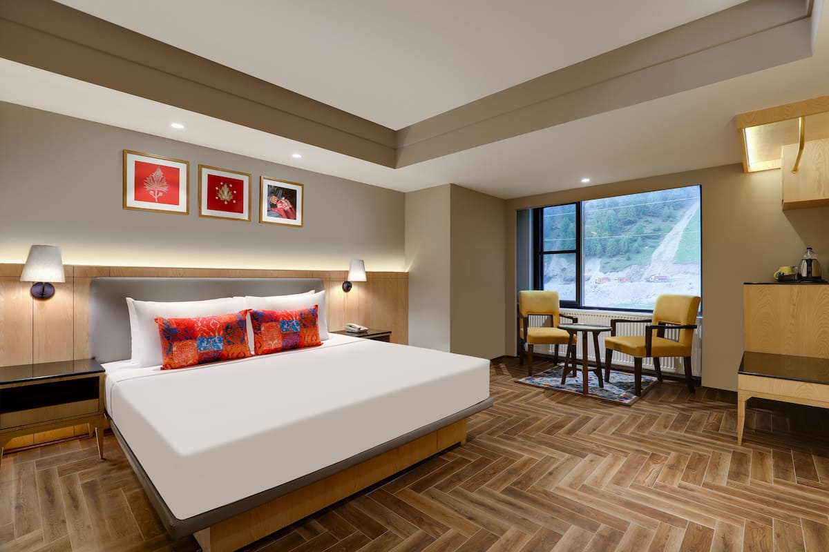 Habitación de hotel moderna con una cama grande, un escritorio y vistas a un paisaje nevado a través de la ventana.