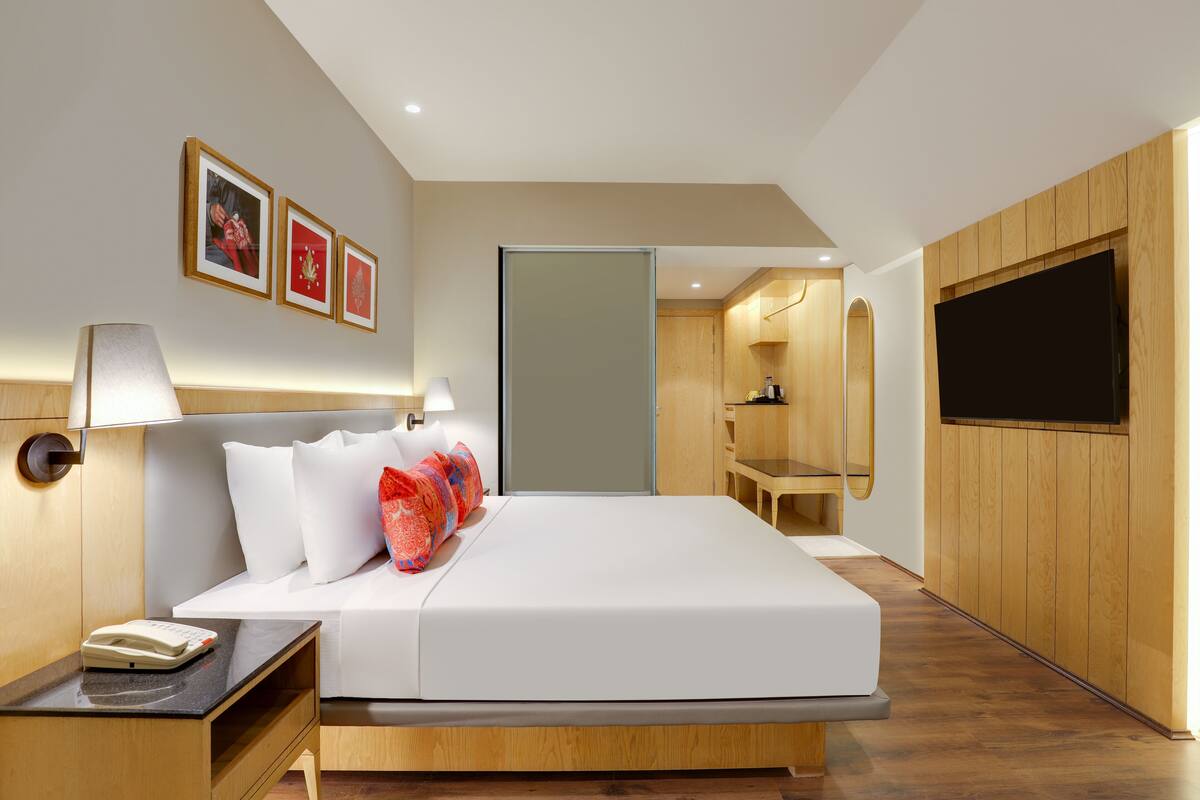 Una habitación de hotel moderna con una cama grande, mesitas de noche, un escritorio y un televisor.