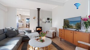 Ein modernes Wohnzimmer mit einer Couch, einem Fernseher, einem Holzschrank, einem Tisch mit Kerze und Blumen sowie einem Kamin.