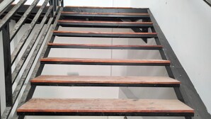 Een trap met houten treden en zwarte metalen leuningen.