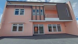 Een modern gebouw met twee verdiepingen, een roze gevel, grote ramen en een balkon.