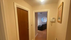 A hallway with wooden flooring, white walls, and a ceiling light. - Immaculate 1-bed Apartment in Birmingham (Birmingham)