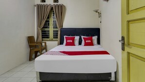 Een net opgemaakt bed met een rood-witte dekbedovertrek en twee kussens met 