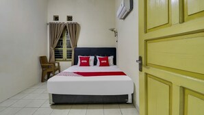 Een slaapkamer met een bed, een stoel, een raam met gordijnen, een airconditioner en een gele deur.