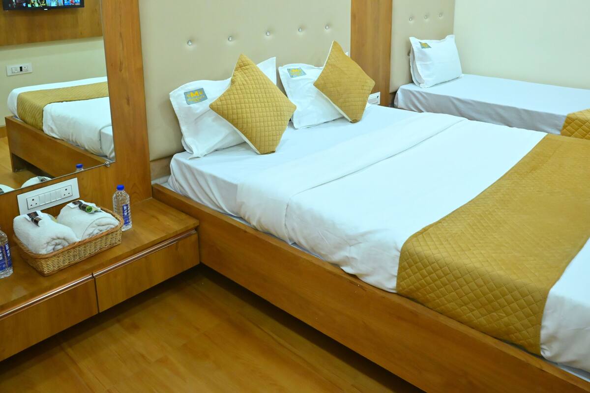 A hotel room with two beds, wooden headboards, white bedding, and a wooden floor.