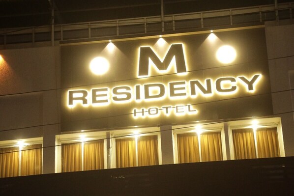 A hotel sign with the name "M RESIDENCY HOTEL" illuminated in bright lights. - Hotel M Residency (Kalyan)