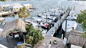 A marina with boats docked, a thatched-roof structure, and a view of the water. - Waterfront Condo Dock Pool Near Duval St (Key West)
