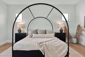 A bed with a black metal frame and a white mattress, flanked by two bedside tables with lamps, in a room with a white wall and a window. - Experience The Westly! Very Clean, Walk to Oldtown (Scottsdale)