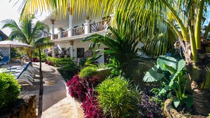 A resort with a pool, palm trees, and a covered walkway. - Natural Kendwa Villa (Kendwa)