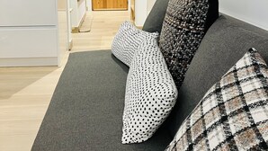 A modern living room with a sofa, patterned cushions, and a wooden door in the background.