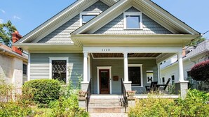 A two-story house with a front porch, a number '1110' above the door, and a small garden area in front.