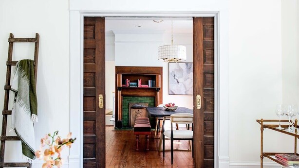 A wooden floor, a dining table with chairs, a bookshelf, and a fireplace.
