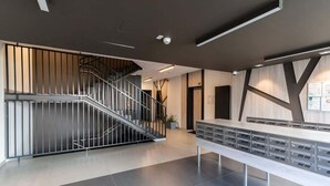 En moderne lobby med trappe, receptionsdisk og opslagstavle på væggen.