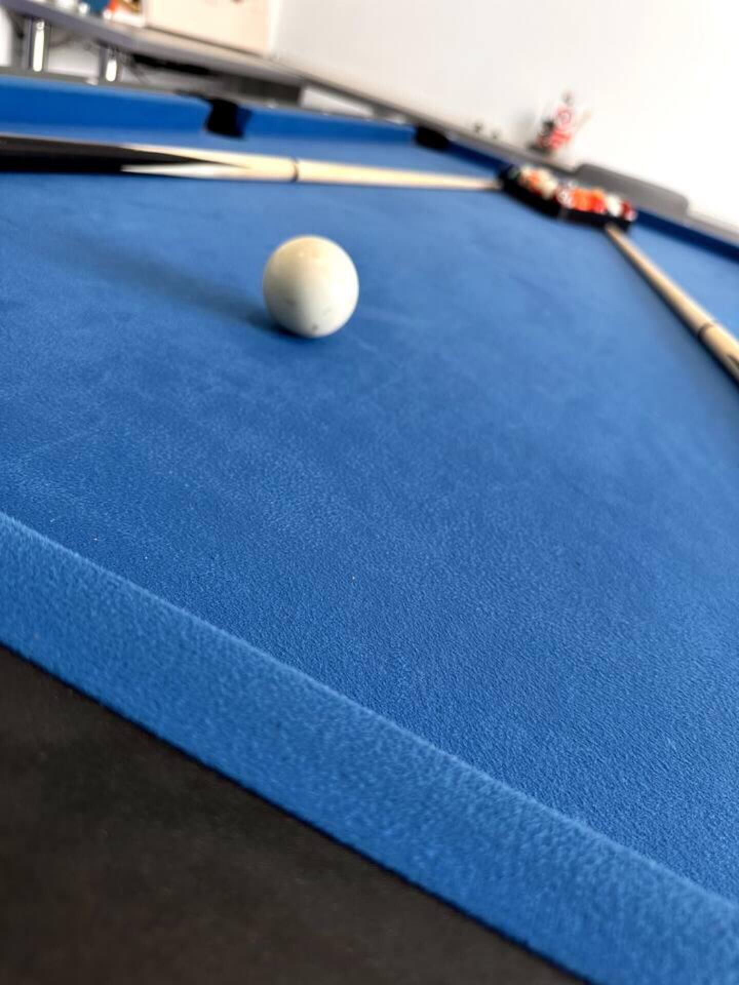 A close-up of a pool table with a white cue ball and a pool cue.