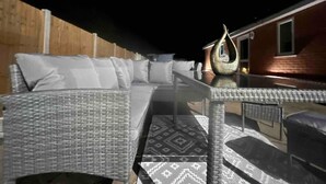 A covered outdoor seating area with wicker furniture and a decorative metal sculpture. - Serenity Haven 4-bed With Hottub,games,gym & More (Colchester)